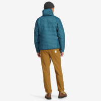 Back model shot of Topo Designs Men's Global Puffer packable recycled insulated Hoodie jacket in "pond blue". 