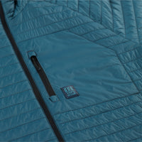 Detail shot of chest zipper pocket on Topo Designs Men's Global Puffer packable recycled insulated Hoodie jacket in "pond blue". 