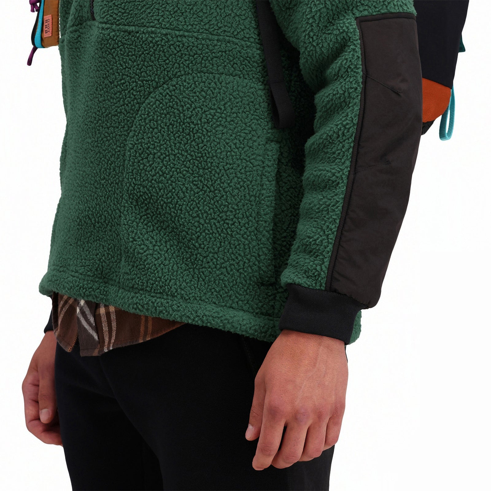 General front model detail shot of hand pockets and sleeve cuff on Topo Designs Men's Mountain Fleece Pullover in "Forest" green.