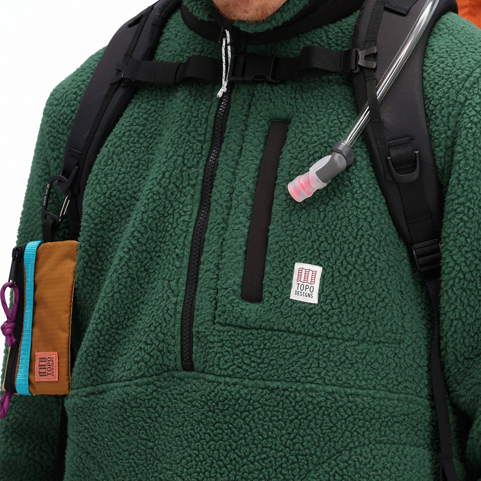 General front model detail shot of zipper chest pocket and logo patch on Topo Designs Men's Mountain Fleece Pullover in "Forest" green.