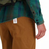 General back model shot of Topo Designs Men's Mountain lightweight hiking Pants Ripstop in "Earth" brown showing logo patch on pocket.