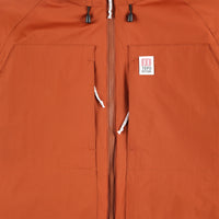 General detail shot of chest zipper pockets on Topo Designs Mountain Puffer Primaloft insulated Hoodie jacket in "Brick" orange