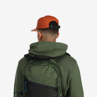 General back model shot of Topo Designs Nylon Camp 5-panel flat brim Hat in "brick" orange