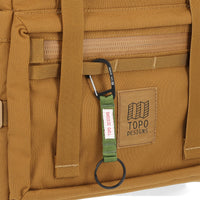 General detail Shot of the Topo Designs Rover Pack Tech in "Dark Khaki" brown showing key clip attached to front daisy chain webbing.
