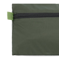 General detail shot of tab and zipper on Topo Designs TopoLite Dopp Kit ultralight toiletry bag for travel in "olive" green.