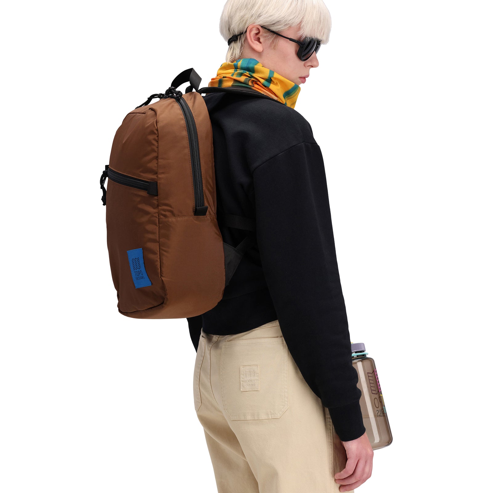 General shot of Topo Designs Light Pack laptop backpack in "cocoa" brown on model shown from side.