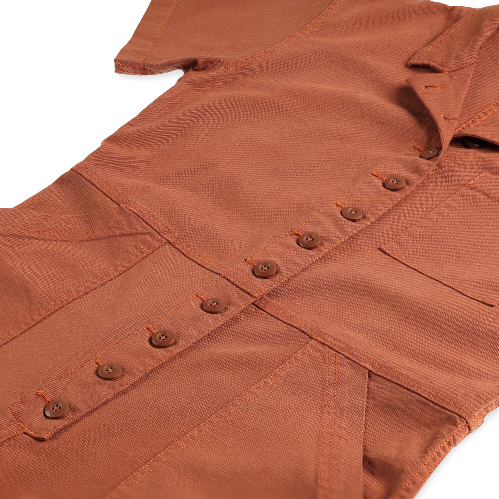 General detail shot of front buttons and pockets on Topo Designs Women's Dirt Coverall 100% organic cotton short sleeve jumpsuit in "brick" orange