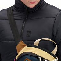 Front model shot of Topo Designs Women's Puffer recycled insulated Jacket in "Black" showing zipper and chest logo.