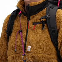 General front detail shot of collar, zipper, and logo patch on Topo Designs Women's Mountain Fleece Pullover in "dark khaki" brown on model.
