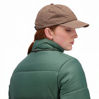 General side model shot of Topo Designs Mountain Ball Cap cotton logo hat in "Dark Khaki" brown.