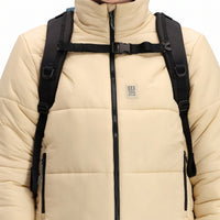 Front model shot of Topo Designs Women's Puffer recycled insulated Jacket in "Sand" white showing zipper, chest logo, and zipper hand pockets.