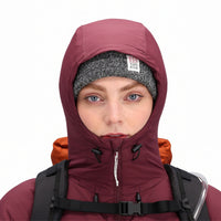 General front model shot of Topo Designs Women's Puffer Primaloft insulated Hoodie jacket in "burgundy" red showing hood details.
