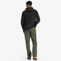 Back model shot of Topo Designs Men's Global Pants lightweight cotton nylon travel pants in "olive" green.