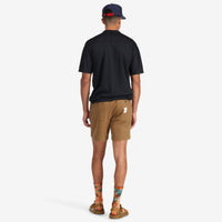 General back of model wearing Topo Designs Men's Mountain organic cotton Shorts in Dark Khaki brown.