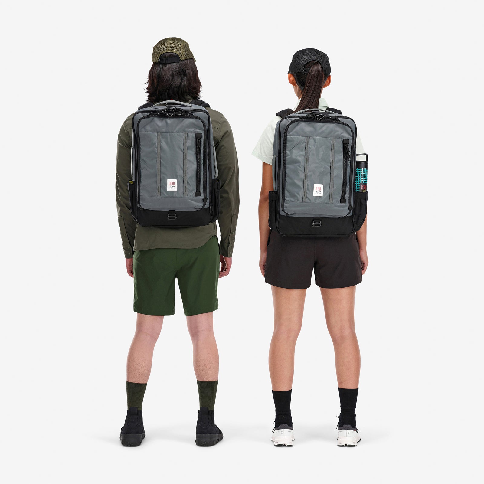 General shot of models wearing Topo Designs Global Travel Bag 30L Durable Carry On Convertible Laptop Travel Backpack in Charcoal gray.