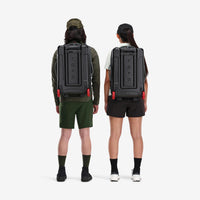 General shot of models wearing Topo Designs Global Travel Bag Roller durable carry-on convertible laptop backpack rolling suitcase in Charcoal gray with removable backpack straps.