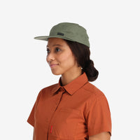 Model wearing Topo Designs Nylon Camp 5-panel flat brim Hat in "olive" green.