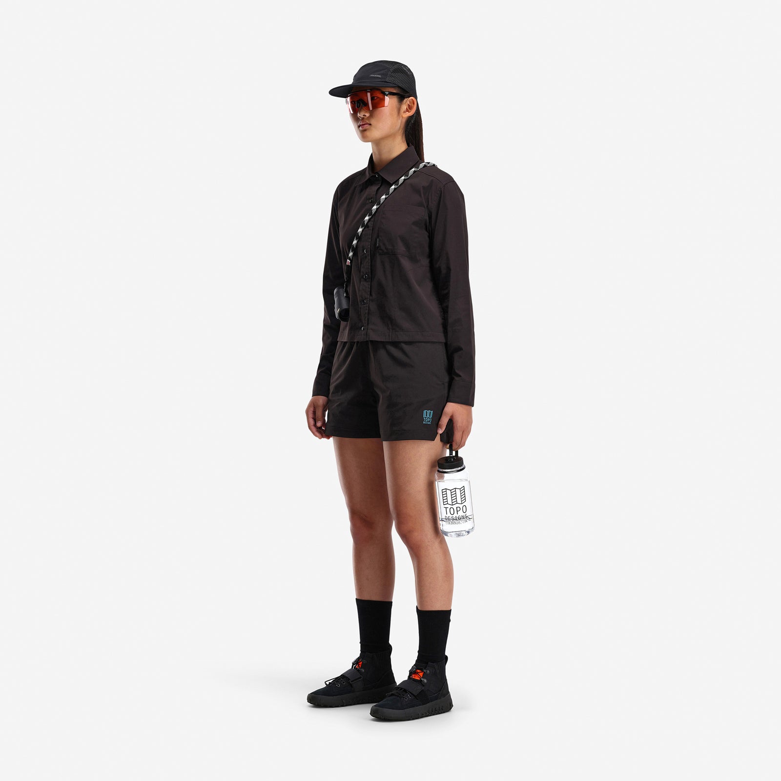 Side model shot of Topo Designs Women's Global long sleeve lightweight snap travel shirt in "black"
