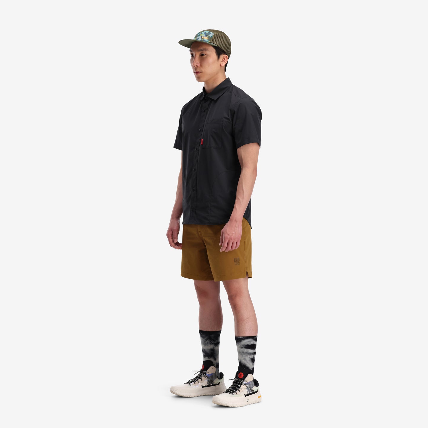 Left side model shot of Topo Designs Men's Global lightweight quick dry travel Shorts in "Dark Khaki" green.