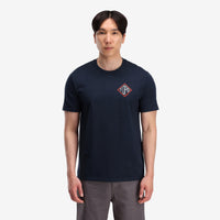 General shot, on model front view of Topo Designs Men's Small Diamond Tee 100% organic cotton short sleeve graphic logo t-shirt in "navy" blue.