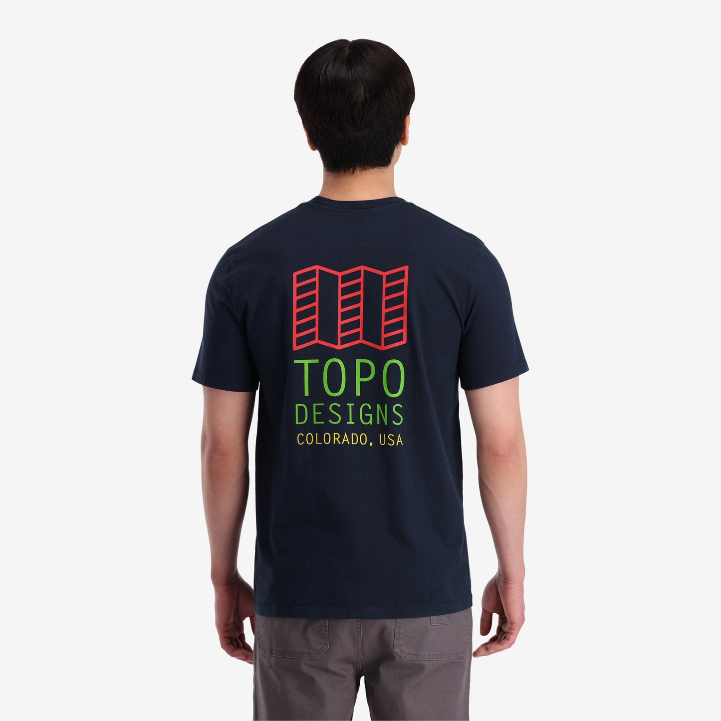 On model back view of Topo Designs Men's Small Original Logo Tee 100% organic cotton short sleeve graphic logo t-shirt in "navy" blue.