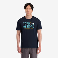 General shot On model front view of Topo Designs Men's Small Diamond Tee 100% organic cotton short sleeve graphic logo t-shirt in "navy" blue.