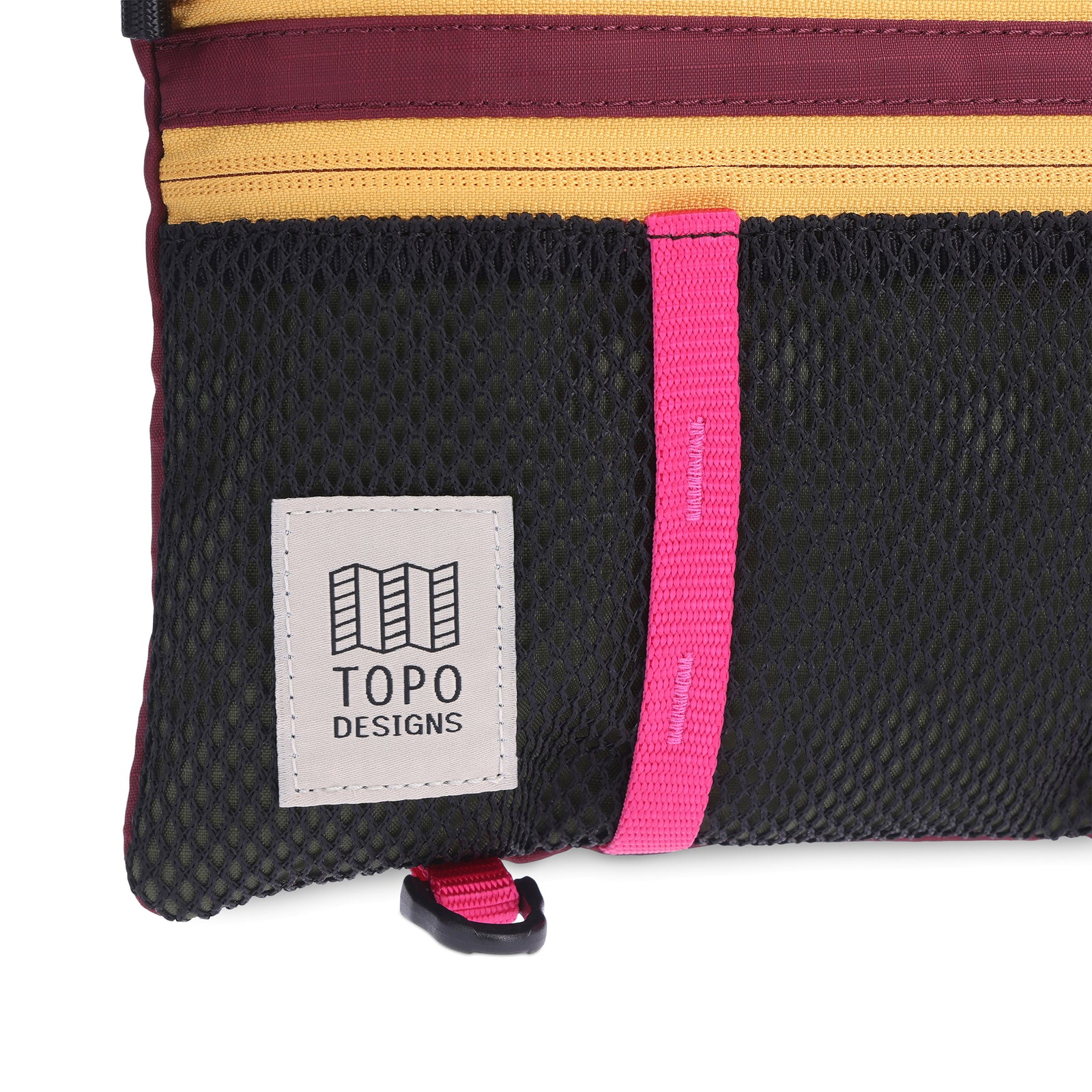 Front, bottom left, logo detail shot of Topo Designs Mountain Accessory crossbody Shoulder Bag in "Olive / Burgundy" lightweight recycled nylon.