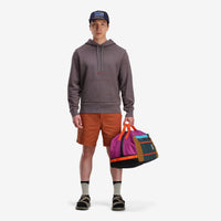 General shot of model wearing Topo Designs Mountain Duffel 40L backpack gear bag in recycled "Botanic Green / Grape" nylon.