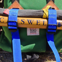 General shot of Topo Designs blue Accessory Straps on a backpack.