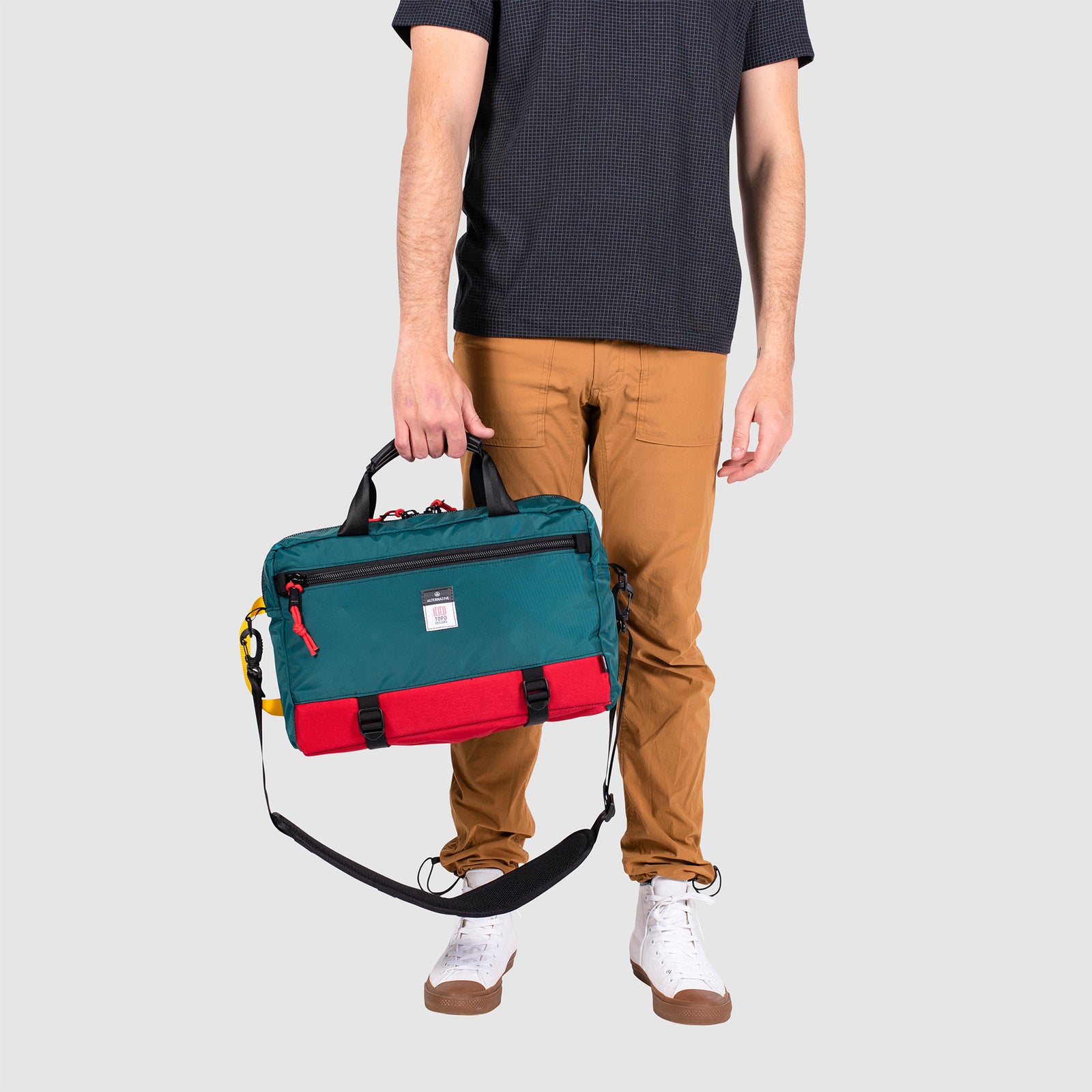 Model shot of Topo Designs x Alternative Commuter Briefcase in red/teal showing briefcase handle carry style