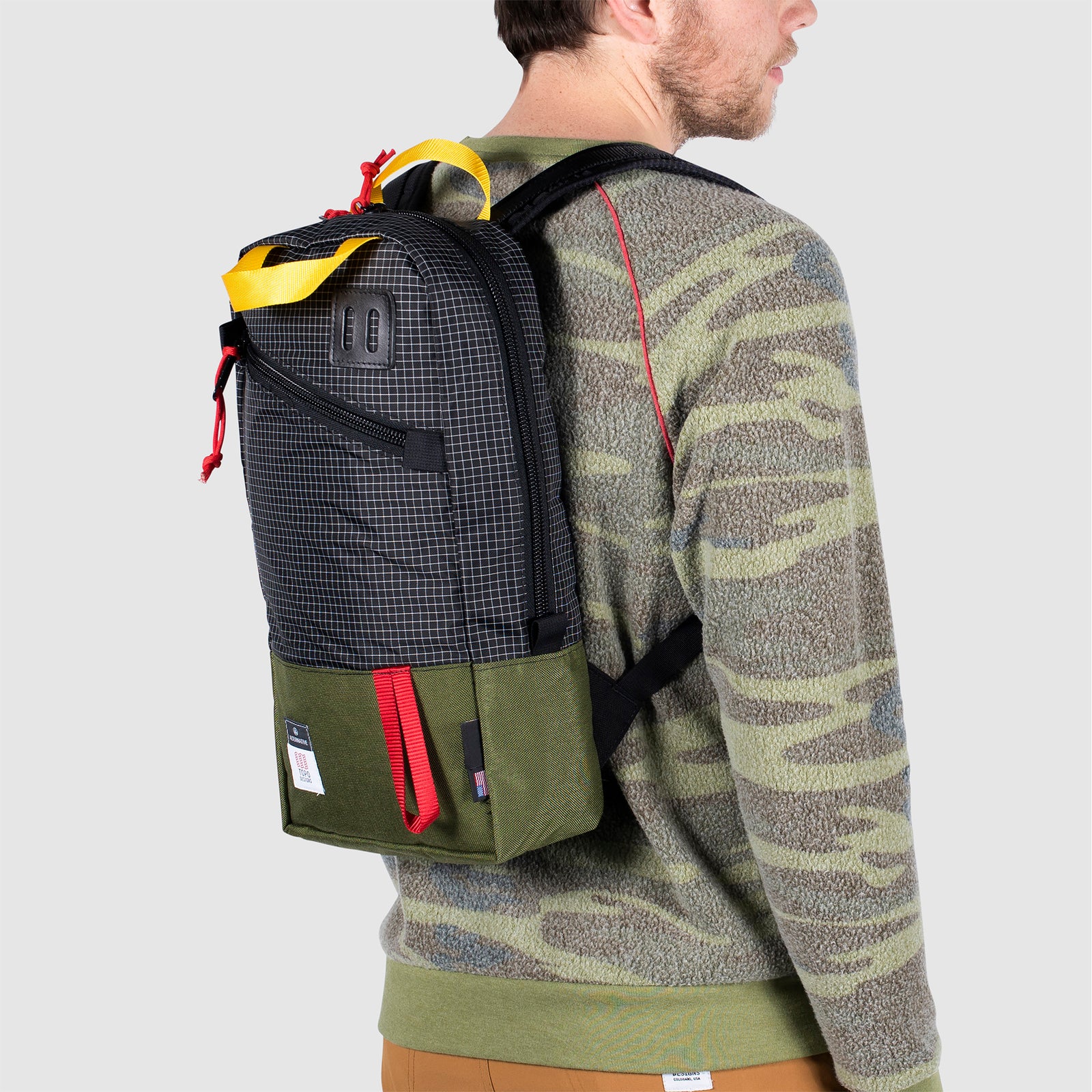 3/4 back model shot of Topo Designs x Alternative Trip Pack in olive/black showing backpack carry style