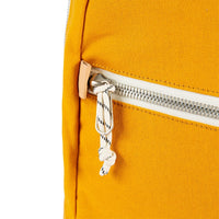 General detail shot of Topo Designs Light Pack in Mustard yellow canvas showing zipper pull tabs.