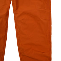 General front detail shot of Topo Designs Women's Lightweight Tech Pants in Brick orange showing articulated knees.