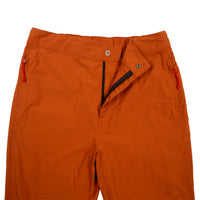 General front detail shot of Topo Designs Women's Lightweight Tech Pants in Brick orange showing zipper fly opening.