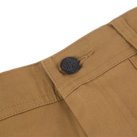 General shot of Topo Designs Men's Global Pants lightweight cotton nylon travel pants in Dark Khaki brown showing logo hardware on fly.