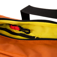 General detail shot of Topo Designs Quick Pack hip fanny pack in Clay orange showing internal key clip and yellow lining.