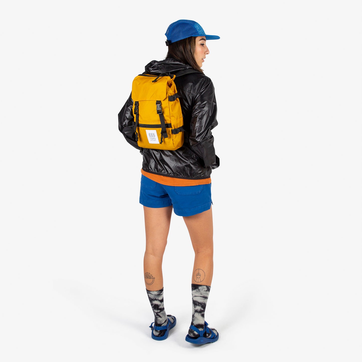 Topo Designs Rover Pack Mini backpack in "Mustard" yellow worn by model with backpack straps.