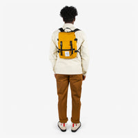 Topo Designs Rover Pack Mini backpack in "Mustard" yellow worn by model with backpack straps.
