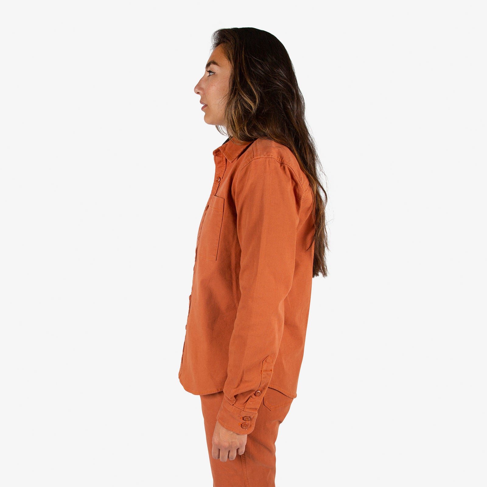 Side model shot of Topo Designs Women's Dirt Shirt & Pants in "Brick" orange. Show on "Peppercorn" & "Black"